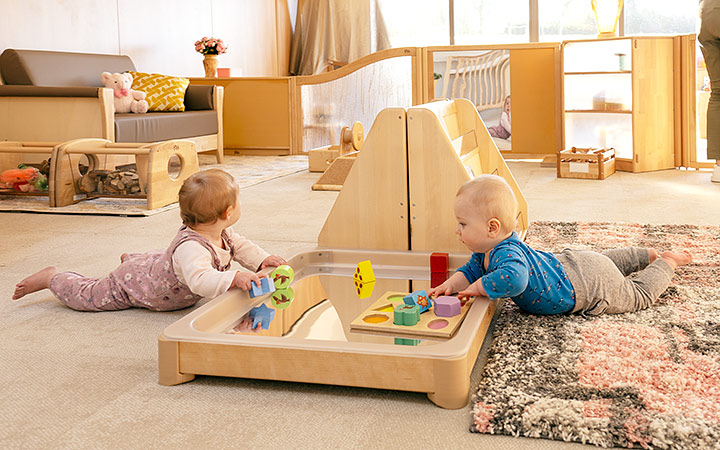 Two babies doing sensory play on the floor in a sensory tray