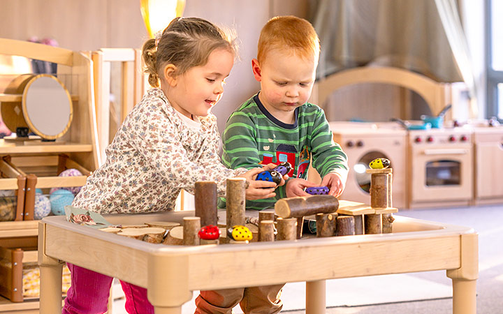 Two-year-olds engaged in sensory play at a solid wood sensory table