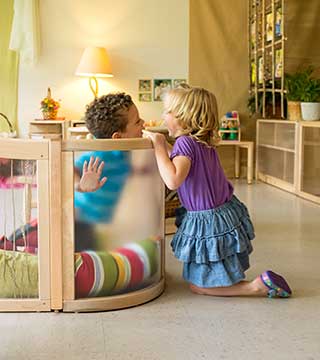 Two children looking at each other over a low transparent room divider