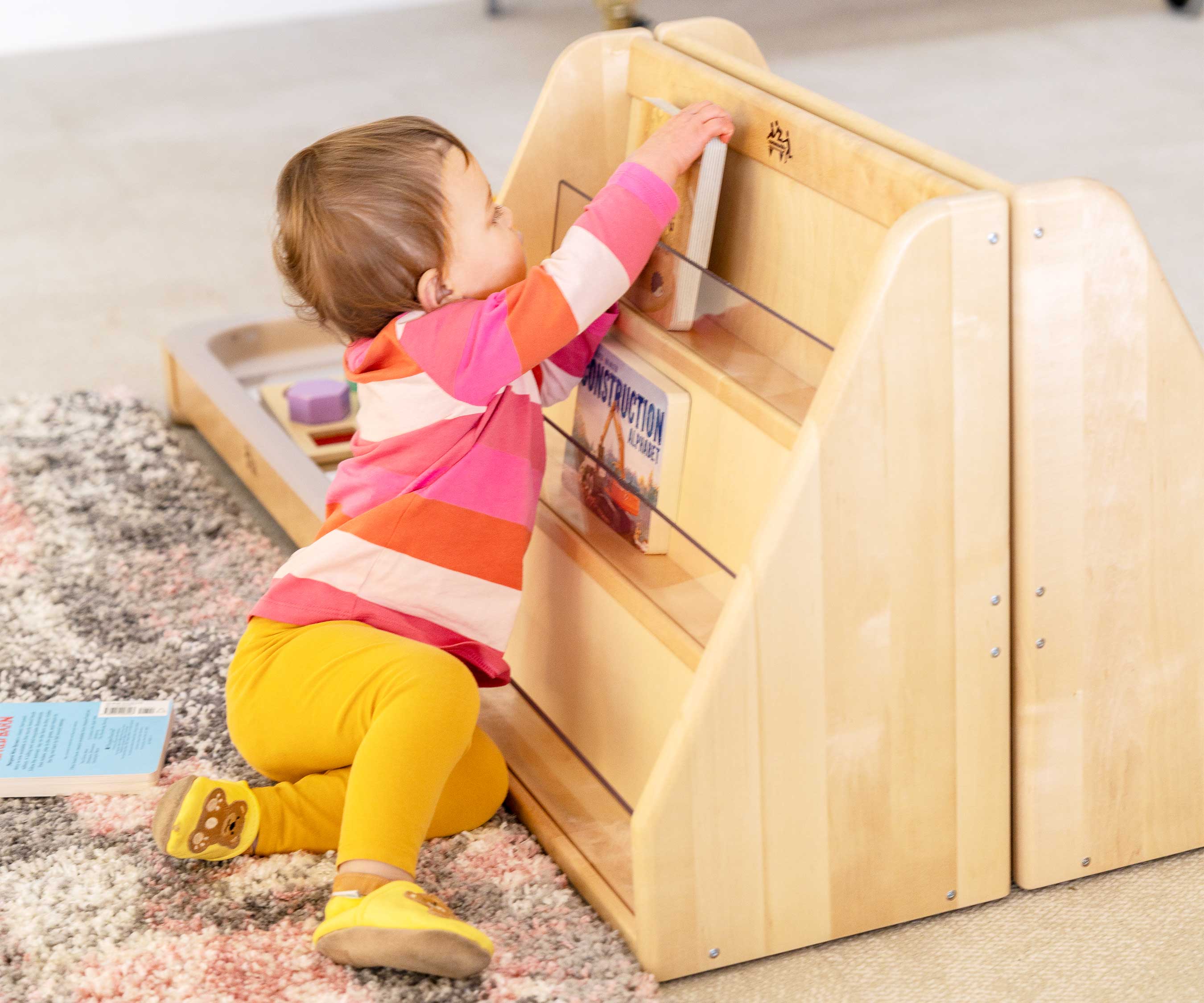girl by toddler bookshelf