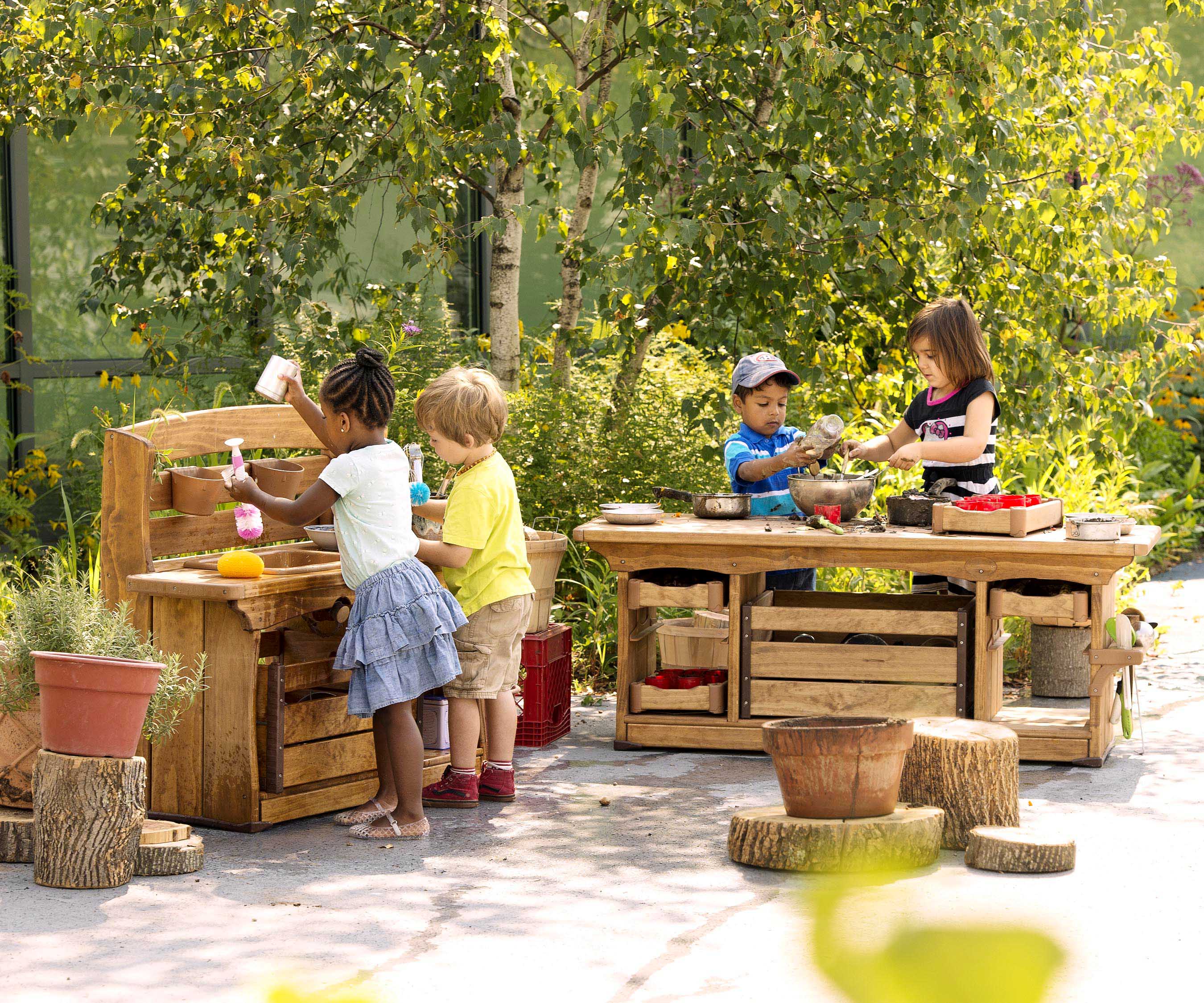 Four children playing with a mud kitchen